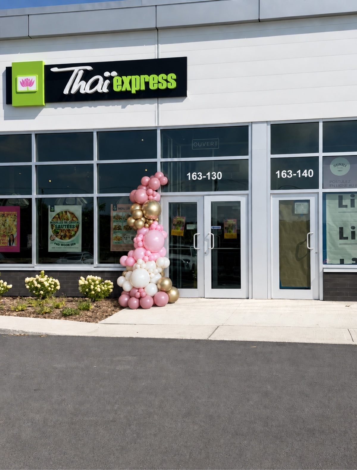 Organic balloon garland in pink, white and gold framing the entrance of a Thai Express restaurant in Ottawa