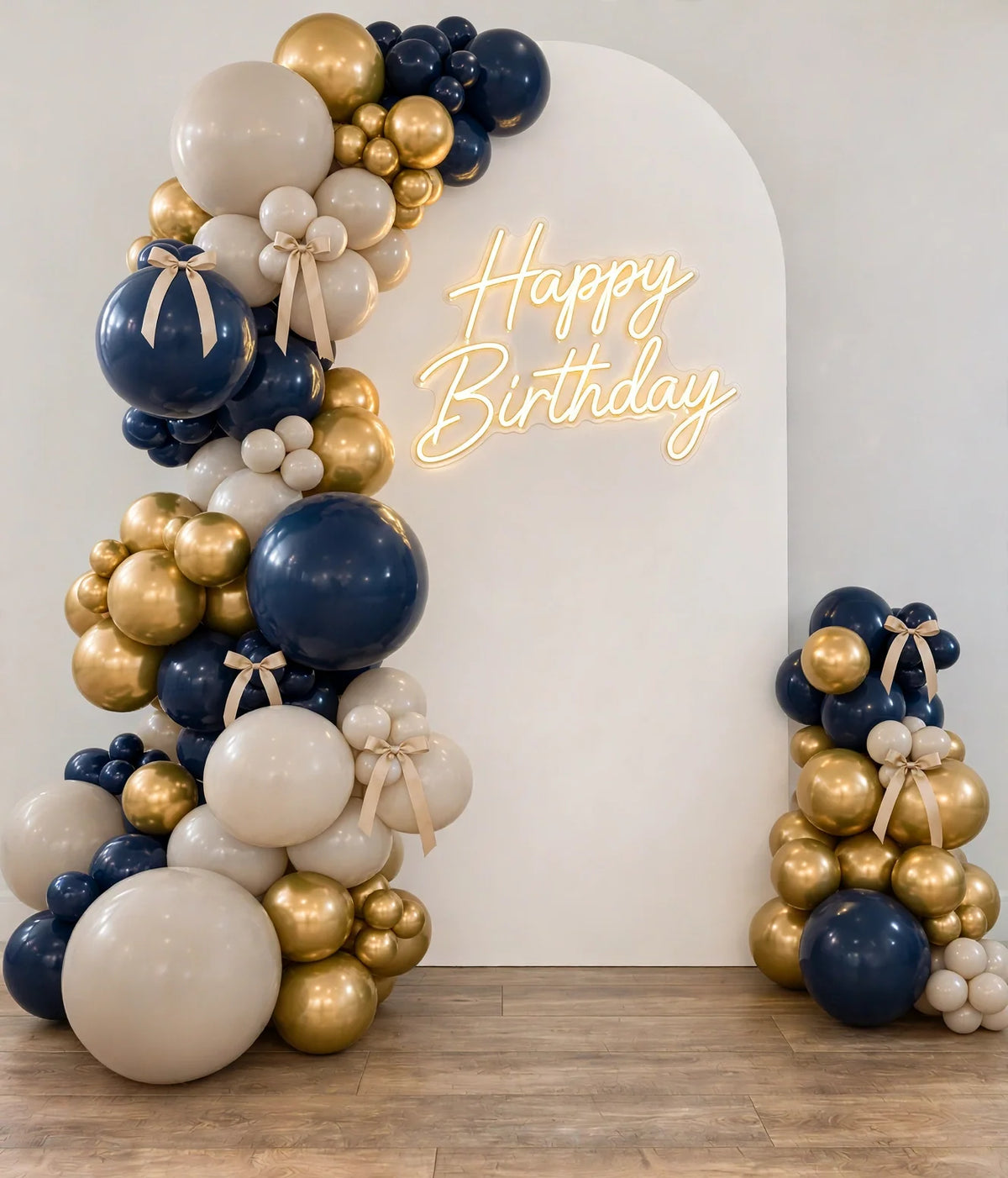 Navy blue, gold and beige balloon garland photo zone with white backdrop and gold LED Happy Birthday sign
