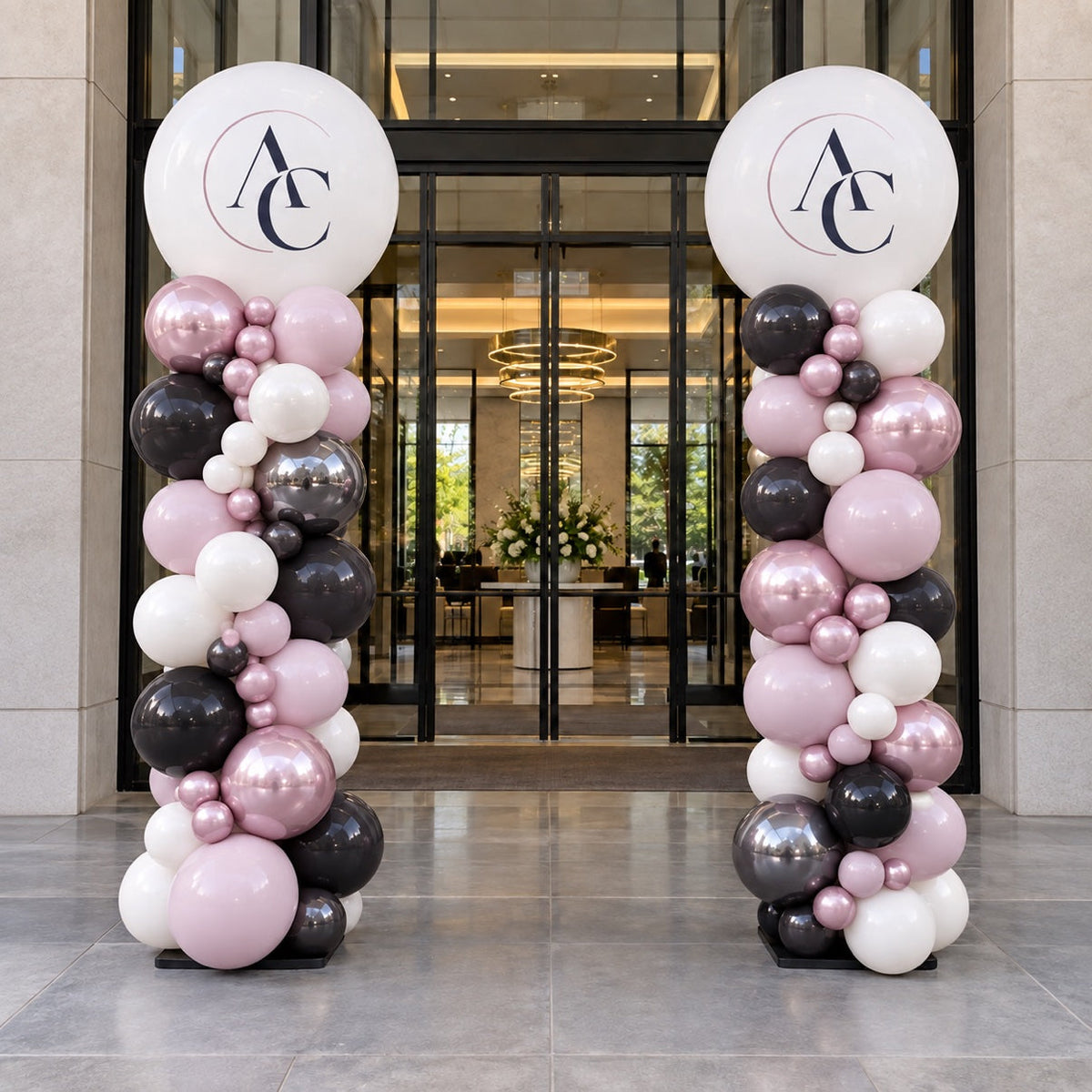 Organic balloon columns with custom logo toppers in black, pink and white at a corporate event entrance in Ottawa