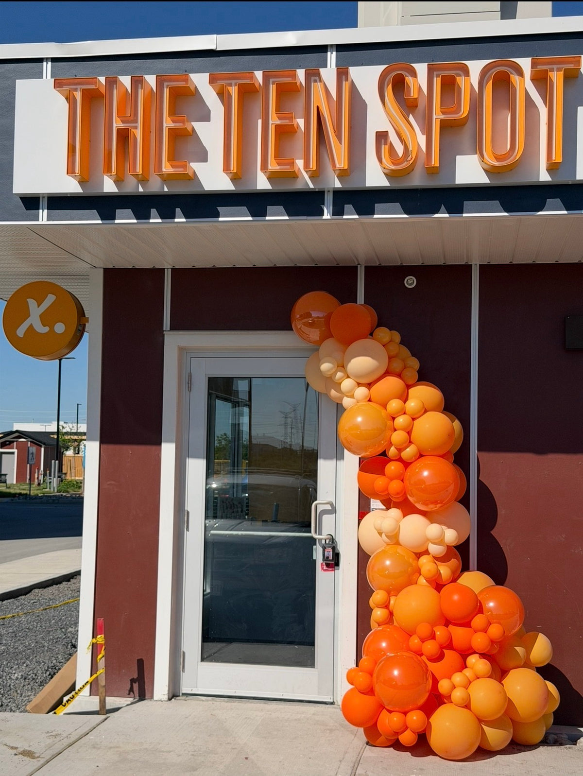 Organic balloon garland in orange and ivory framing the entrance of The Ten Spot store in Ottawa
