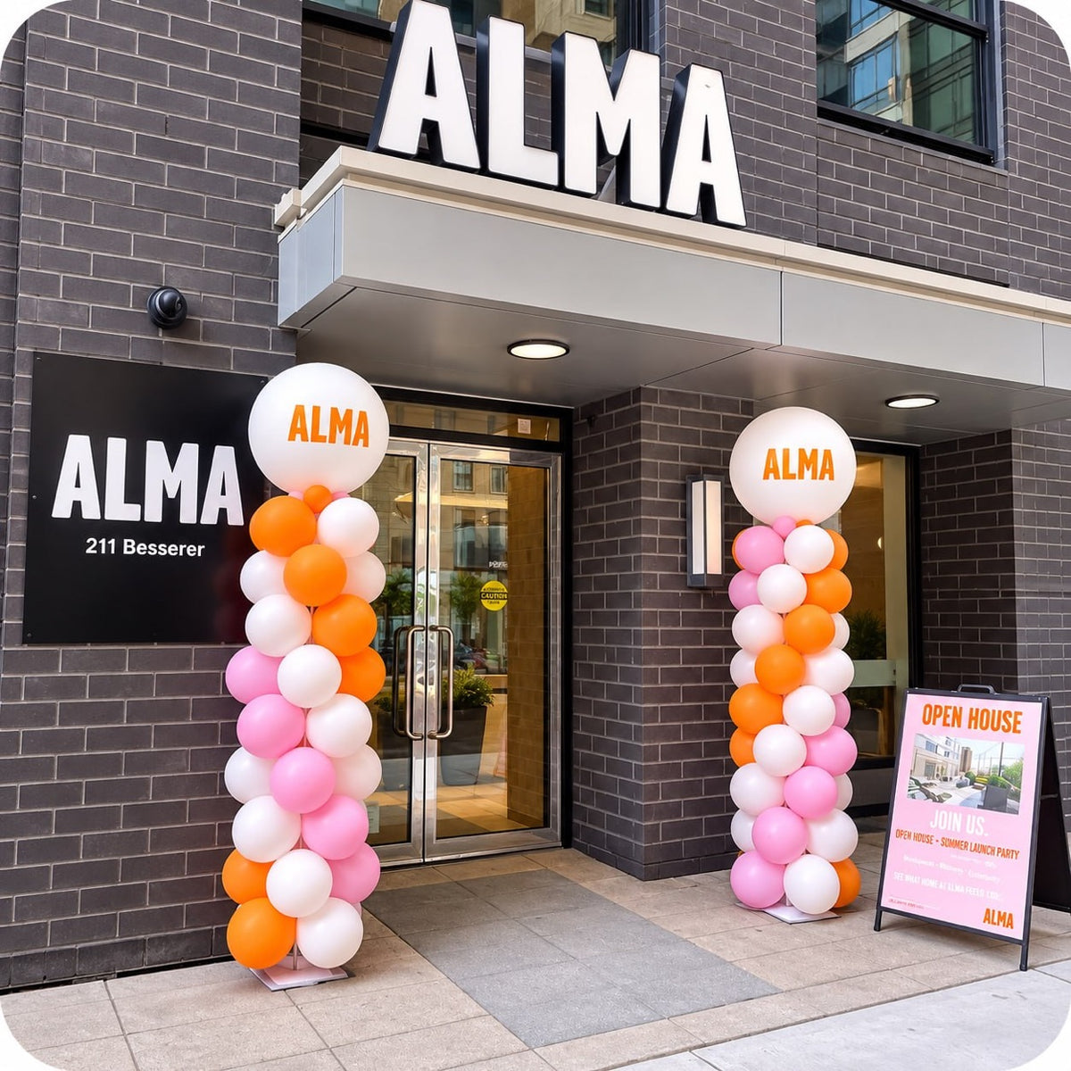 Classic spiral balloon columns / pillars in pink, orange and white with ALMA logo toppers at an ALMA open house entrance