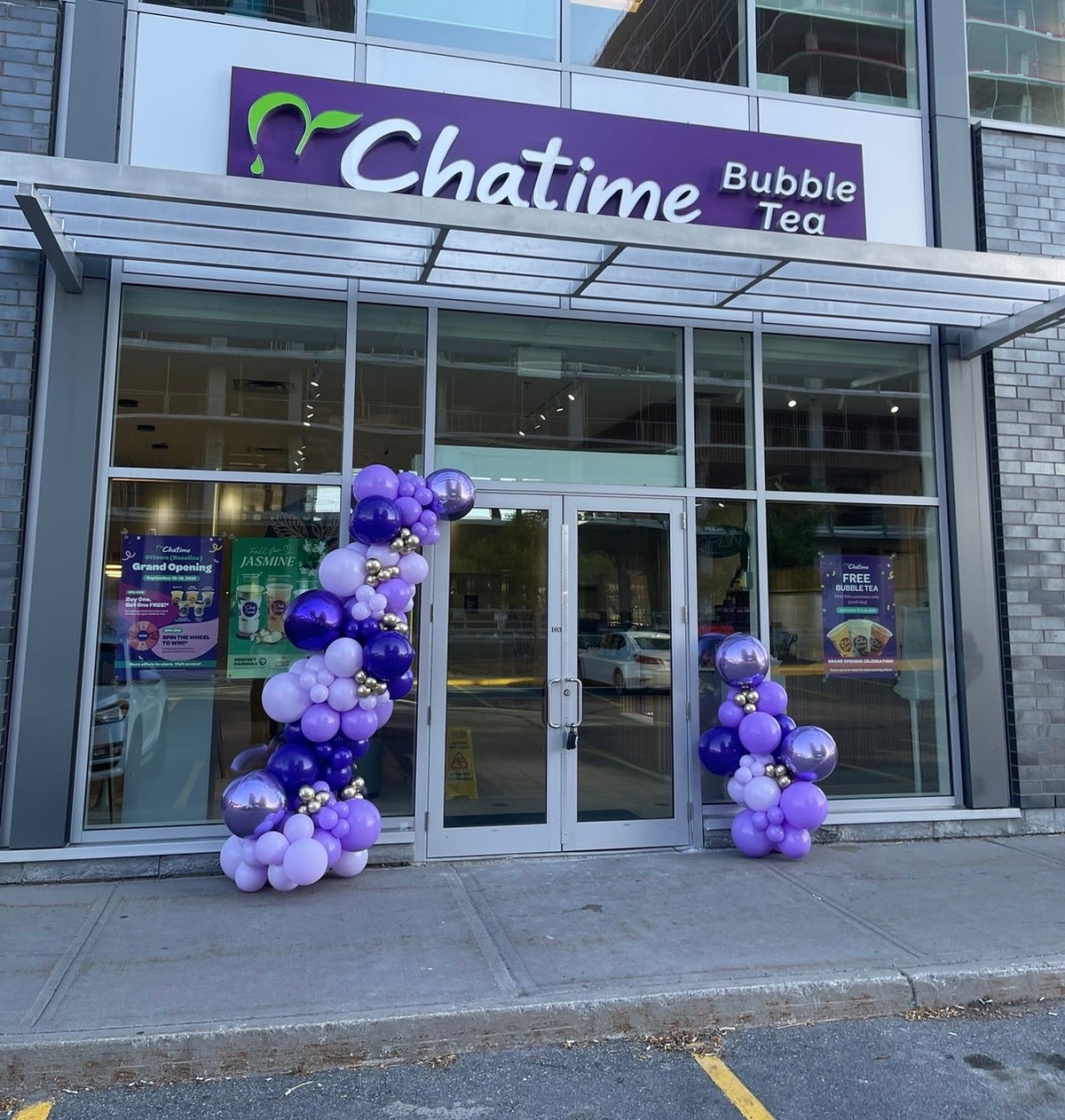 Organic balloon garland in purple, lavender and chrome silver framing the entrance of a Chatime bubble tea store in Ottawa