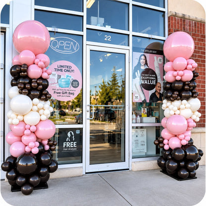 Pair of organic balloon columns / pillars in pink, chocolate brown, white and black flanking a salon entrance