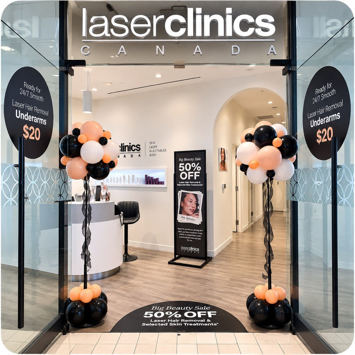 Two balloon topiaries on tall poles with streamers in black, peach and white at a Laser Clinics store entrance