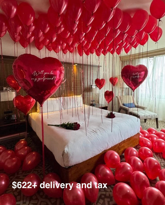 Romantic hotel room proposal setup with red helium balloons on the ceiling, giant red heart foil balloons with Will you be my girlfriend inscription and roses on the bed