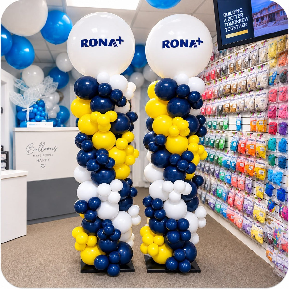 Pair of organic balloon columns / pillars in navy blue, yellow and white with RONA logo toppers inside a store
