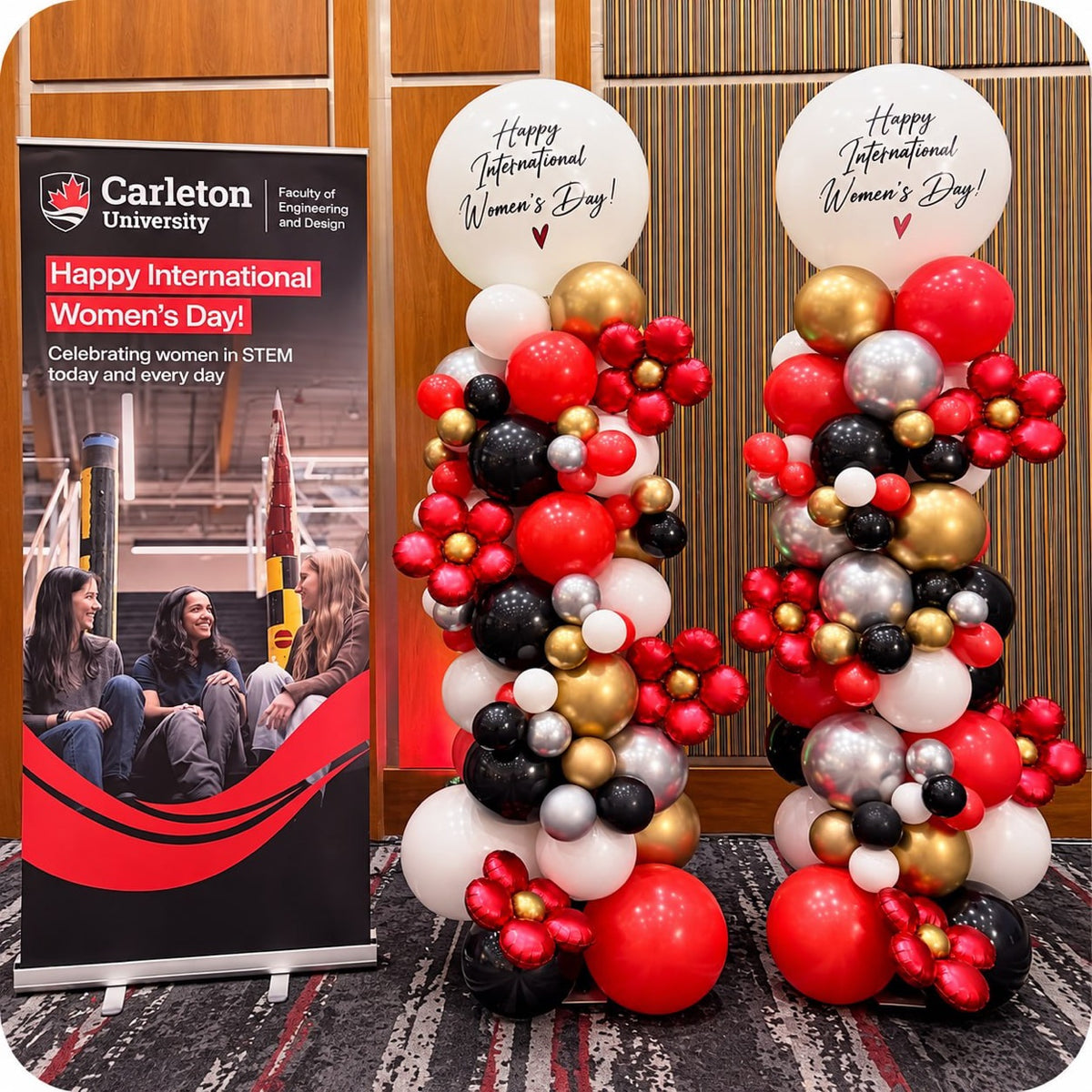 Two organic balloon columns / pillars in red, black, gold and white with Happy International Women's Day toppers at a Carleton University event