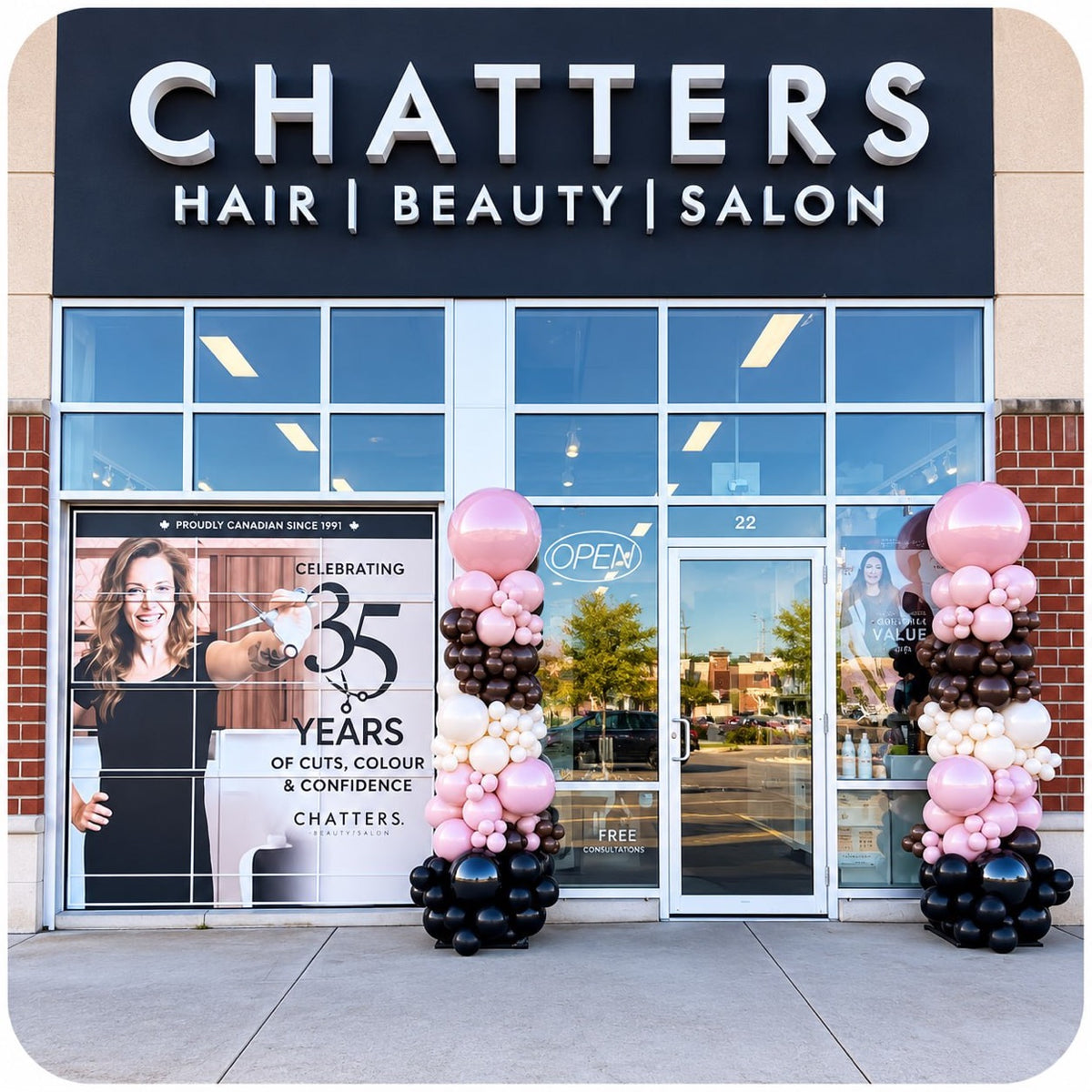 Two organic balloon columns / pillars in pink, brown, white and black at a Chatters salon storefront celebrating 35 years