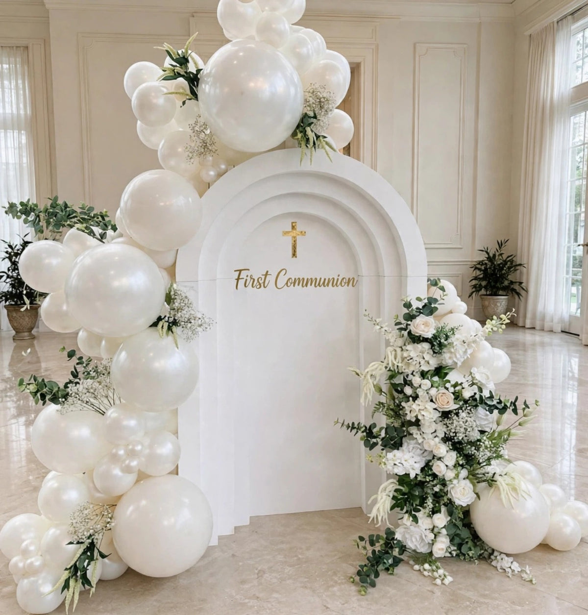 White First Communion balloon backdrop with 3D arch panel, pearl white balloon garland, white flowers and gold cross