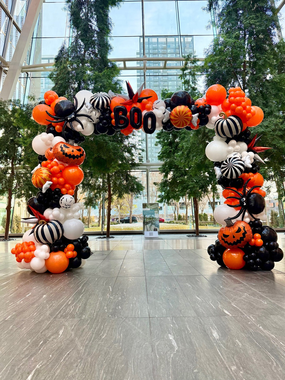 Halloween balloon arch in orange, black and white with BOO letters, pumpkins, spiders and ghosts
