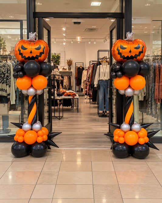 Halloween twisted balloon columns with jack-o-lantern pumpkin foil toppers in orange black and silver