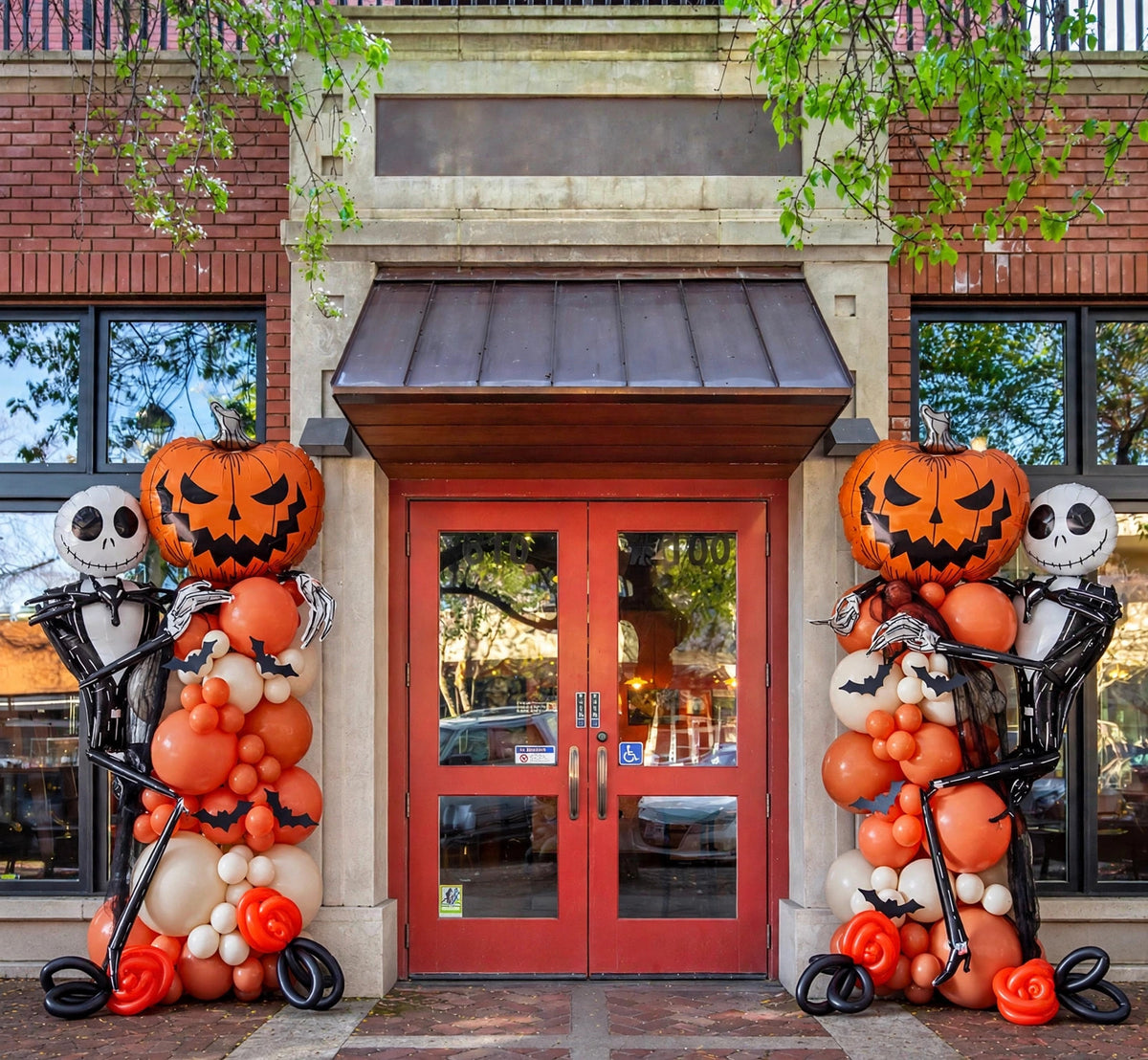 Halloween balloon columns with pumpkin and skeleton foil balloons, orange ivory and black, at a storefront entrance