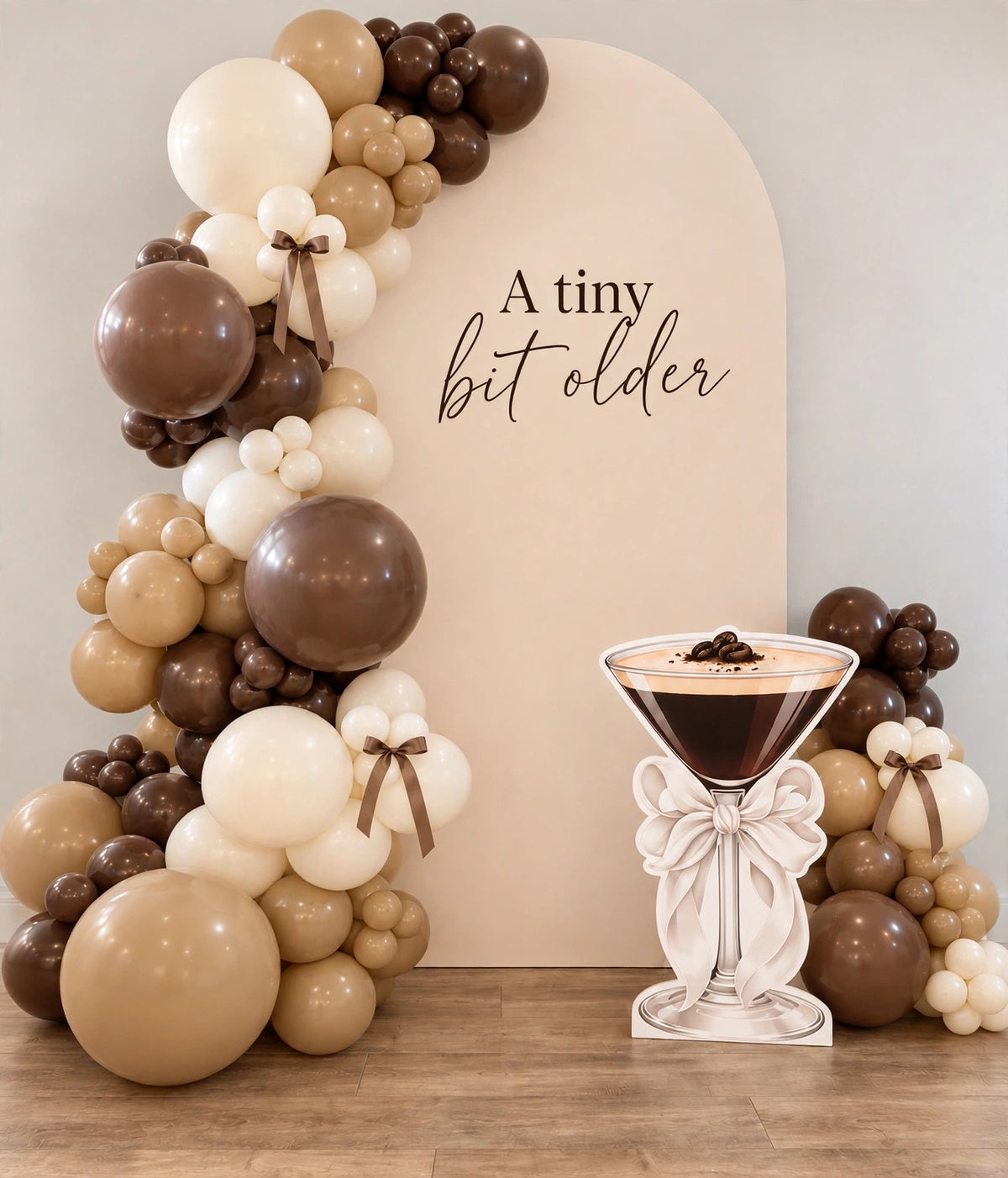 A tiny bit older birthday balloon backdrop with espresso martini cutout and bows